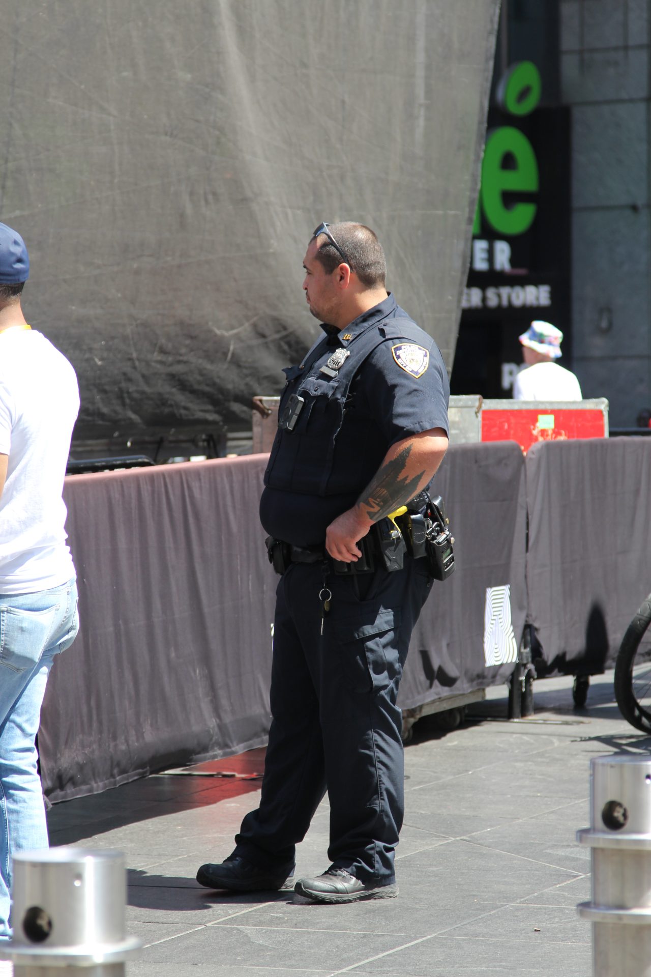 Uniformed NYPD officer with a visible forearm tattoo on patrol in New York City