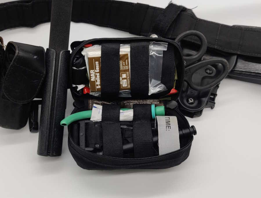 Open belt-mounted police first aid pouch with tourniquet, trauma dressing and medical shears