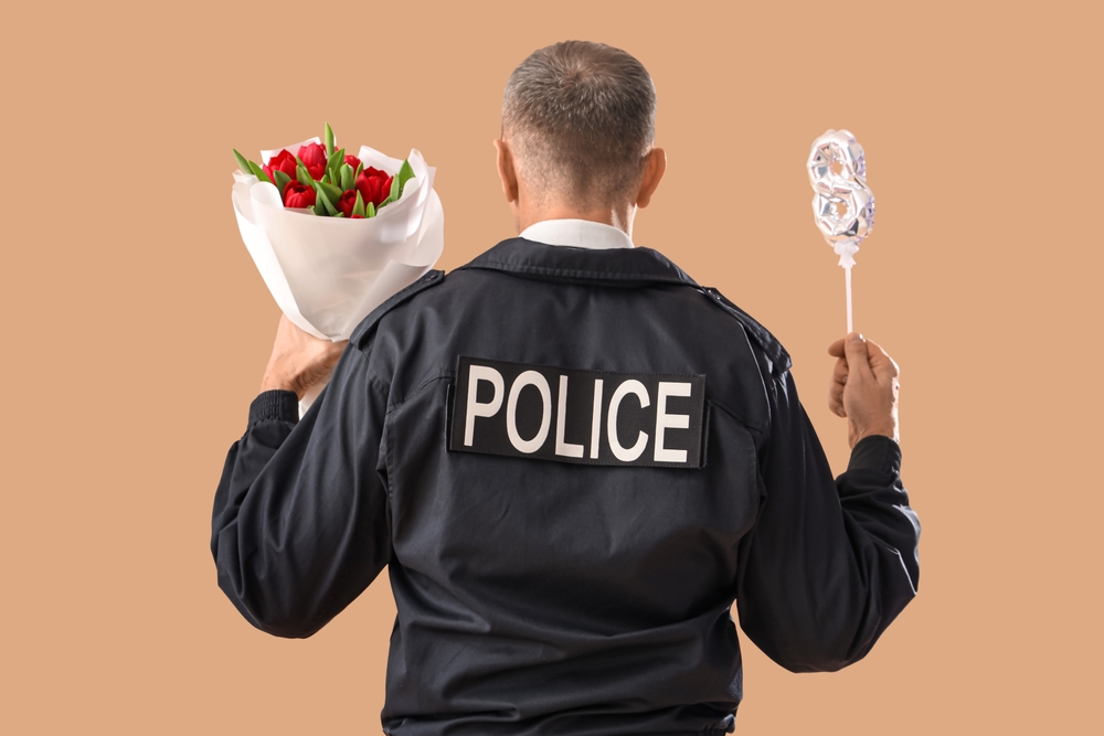 Policeman with balloon in shape of figure 8 and flowers