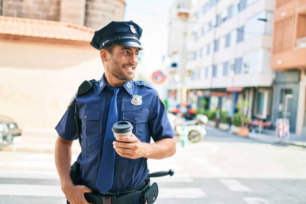 Young policeman wearing police uniform smiling happy