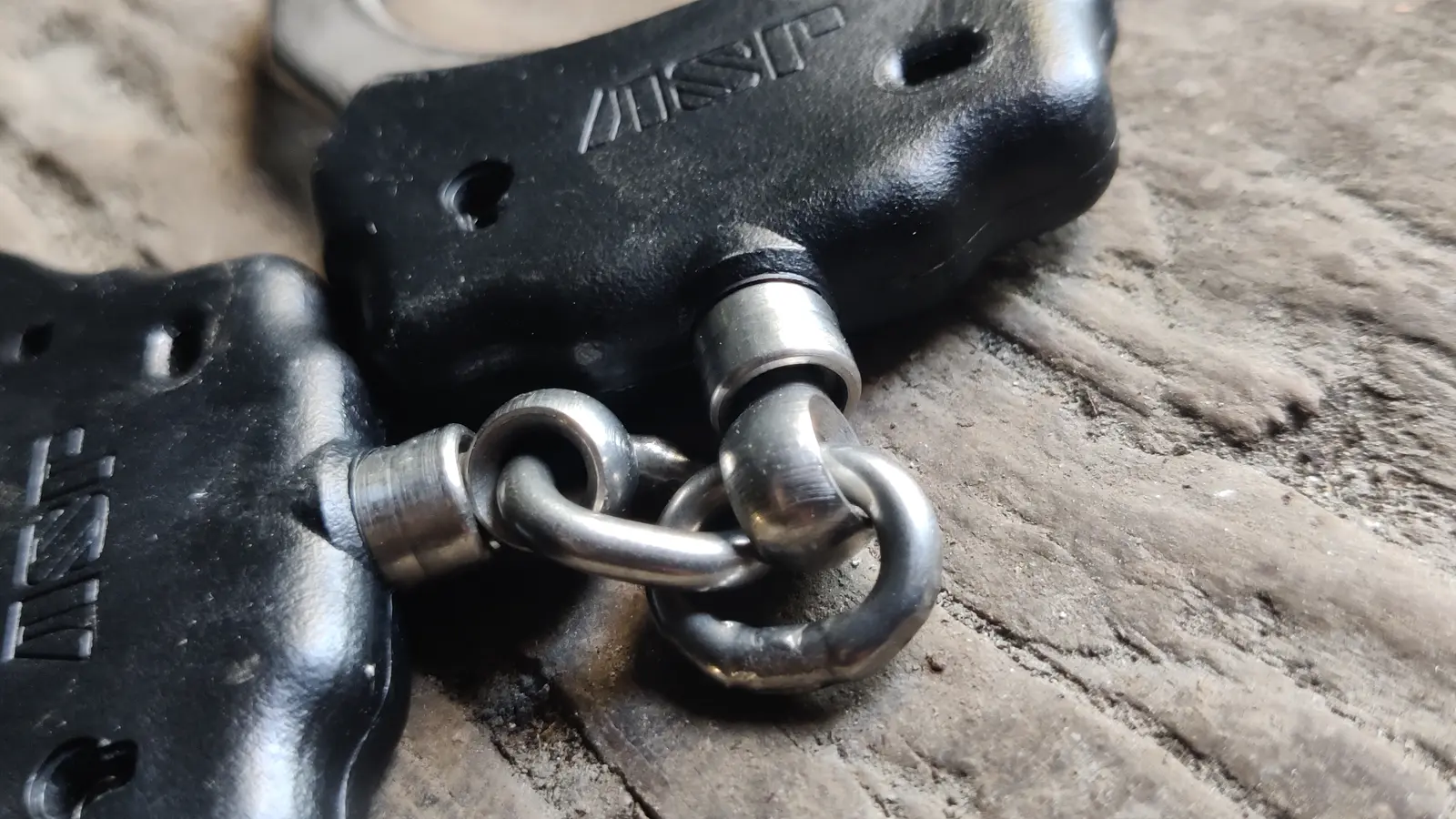 Close-up of chain connectors on two black handcuffs