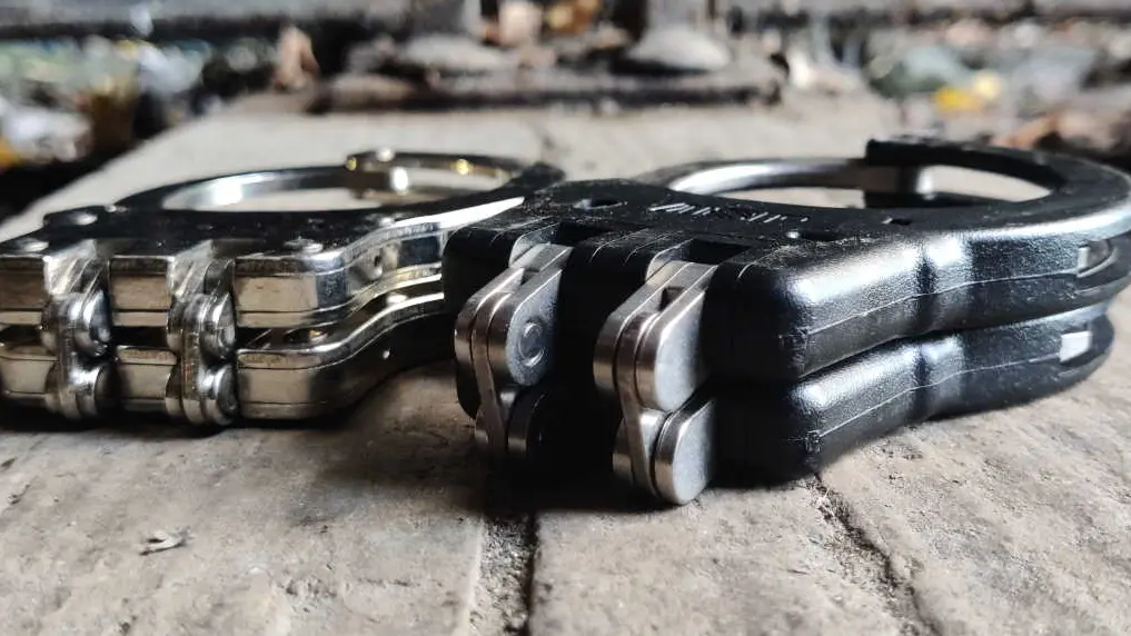 Several folded hinged handcuffs showing different finishes and designs
