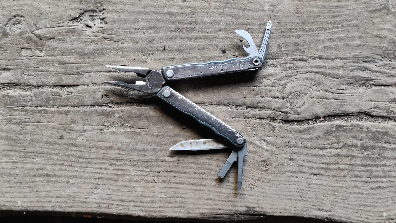 Open stainless steel multi-tool displayed on a wooden surface